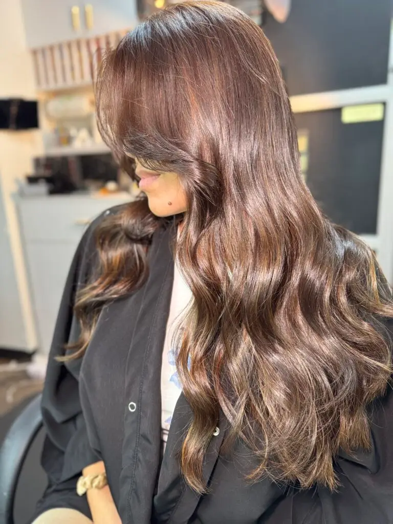 Glossy chocolate brown balayage styled with soft waves